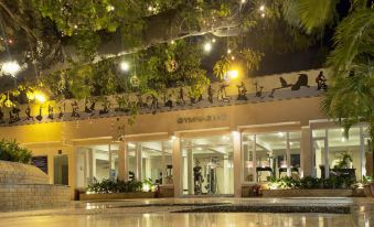 a modern building with glass windows and doors , surrounded by trees and lit up at night at Palace Hotel