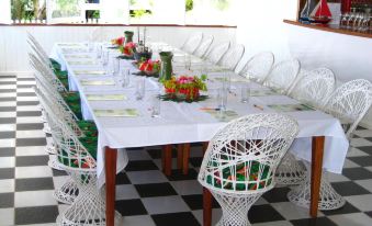 a long dining table set with white chairs and a black and white checkered floor at Driftwood Resort