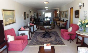 a spacious living room with various furniture , including two pink chairs , a coffee table , and a rug at Whale Watchers Inn