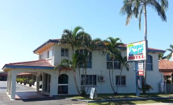 a white building with palm trees in front of it , possibly a motel or an office at Tropic Coast Motel