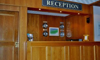 a reception area with a wooden counter , a framed picture on the wall , and various cups and bowls displayed at Abbotsford Hotel