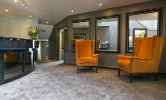 a modern living room with two yellow armchairs , a gray carpet , and large windows at The Cove