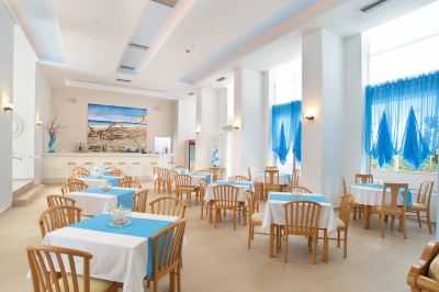 a large , well - lit dining room with multiple tables and chairs arranged for a group of people at Hotel Summery