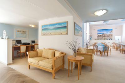 a living room with wooden furniture , including a couch and two chairs , and a dining table at Hotel Summery