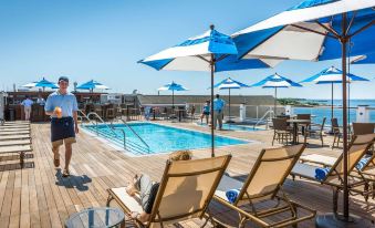 a large outdoor swimming pool surrounded by lounge chairs and umbrellas , providing a relaxing atmosphere for guests at Beauport Hotel Gloucester