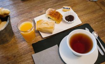a dining table with a cup of tea and a plate of pastries , accompanied by a glass of orange juice at Hotel Belveder