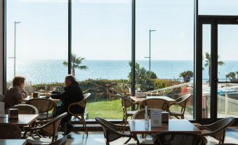 a man sitting at a table in front of a large window overlooking the ocean at Hotel Flamingo