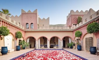 a large pink and white building with a pool of red flowers in front of it at Kasbah Tamadot