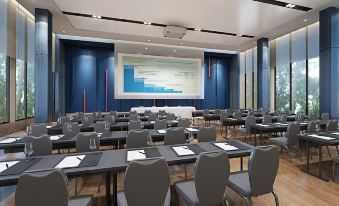 a large conference room with rows of chairs and a projector screen at the front at Rattanachol Hotel