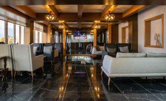 a luxurious waiting room with white couches , wooden ceiling , and black marble flooring , as well as a television mounted on the wall at Gaye City Hotel