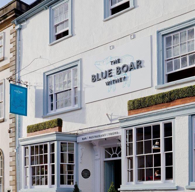 "the exterior of a white building with blue trim , featuring a sign that reads "" the blue boar .""." at The Blue Boar