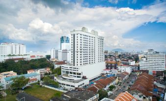 a tall white building with a satellite dish on top is surrounded by other buildings and trees at Cititel Penang