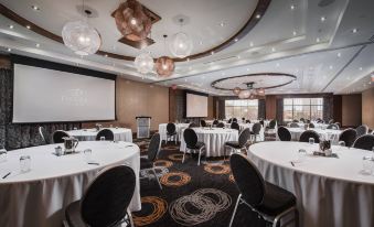 a large conference room with multiple round tables , chairs , and a projector screen , set up for a meeting or event at Delta Hotels by Marriott Waterloo
