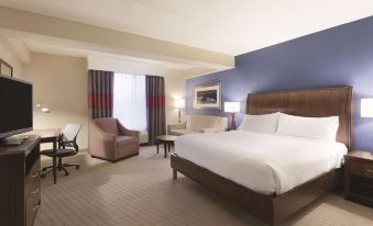 a large bed with white linens is in a room with blue walls and furniture at Hilton Garden Inn Falls Church