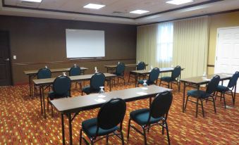 a conference room with rows of tables and chairs , a projector screen , and yellow curtains at Courtyard Middlebury
