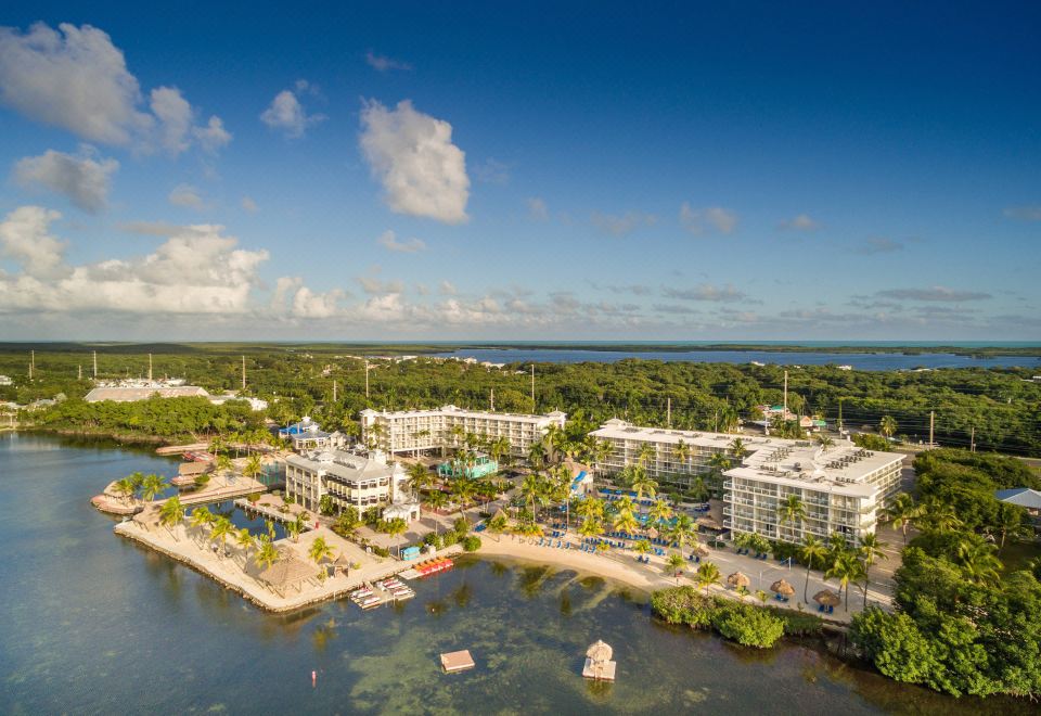 aerial view of a resort on a beach with boats in the water , surrounded by lush greenery and buildings at Reefhouse Resort and Marina