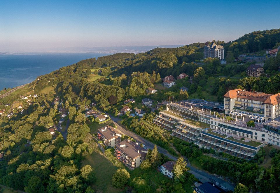 aerial view of a large building surrounded by trees , with a body of water in the background at Le Mirador Resort and Spa