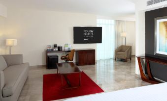 a modern hotel room with a red rug , wooden desk , and a large screen tv at Four Points by Sheraton Veracruz