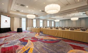 a large conference room with multiple tables and chairs , a colorful carpet , and multiple hanging lights at DoubleTree by Hilton Atlanta Airport