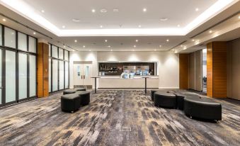 a large room with a gray carpet and black couches , a counter , and windows on one side at Quality Hotel Rules Club Wagga