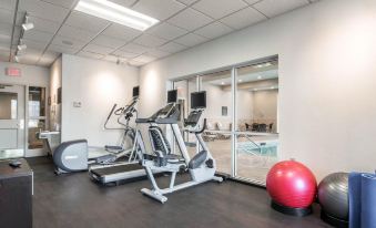a well - equipped gym with various exercise equipment , including treadmills and stationary bikes , as well as a pool in the background at Park Manor Hotel