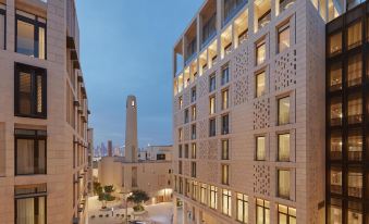 a modern city street with tall buildings and a tall clock tower in the background at Mandarin Oriental, Doha