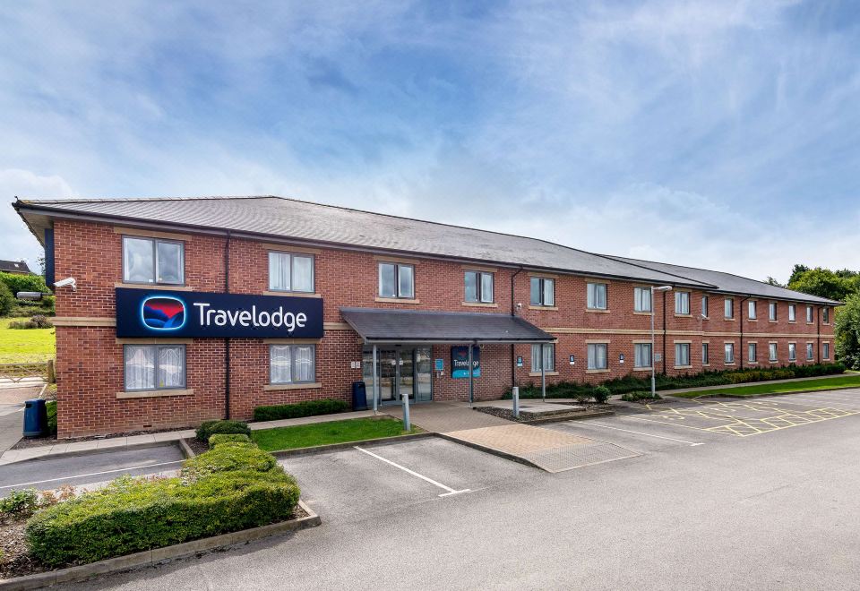 a travelodge hotel with its sign and parking lot , under a clear blue sky at Travelodge Ashbourne