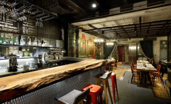 a modern restaurant with a long wooden table and stools , red chairs , and a large wall mural at Hotel The Public - Special Category