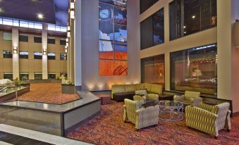 a modern hotel lobby with various seating options , including couches , chairs , and a large painting on the wall at Holiday Inn Manitowoc