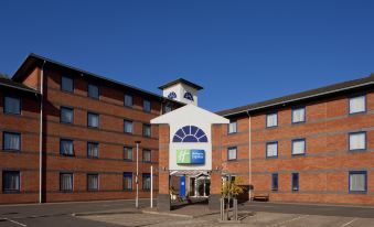 a large brick building with a clock tower and a blue and white sign on the front at Holiday Inn Express Droitwich Spa