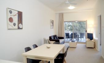 a living room with a dining table , chairs , and a sliding glass door leading to a balcony at Jacana Apartments