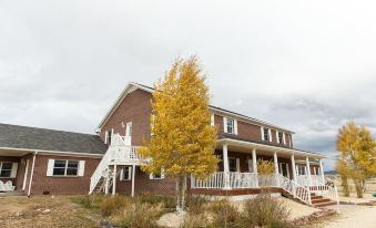 a large house with a white porch and yellow tree in front of it , set against a cloudy sky at Lamp Post Lodge