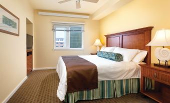 a hotel room with a king - sized bed , a tv , and a window overlooking the city at WorldMark Long Beach