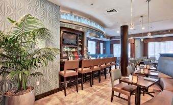 a modern restaurant with a bar area and dining tables , where people are seated and enjoying their meals at Hilton Garden Inn Irvine Spectrum Lake Forest