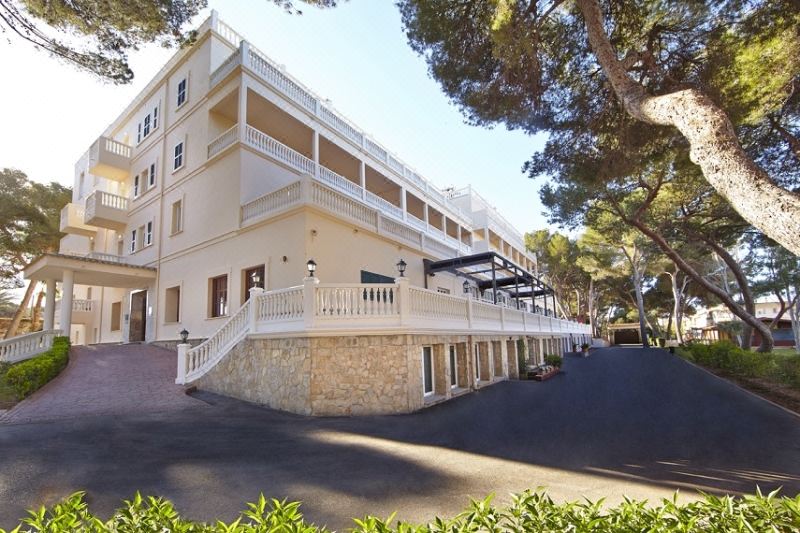 a large , white building with a stone staircase leading up to it , surrounded by trees at Mll Palma Bay Club Resort