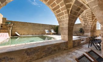 The outdoor patio features a pool and a stone archway that leads to the living room at Casino Doxi Stracca by BarbarHouse