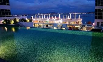 At night, there is a large swimming pool with illuminated lights that offers a scenic view of the city and surrounding buildings at JK Maritime Luxury Suite