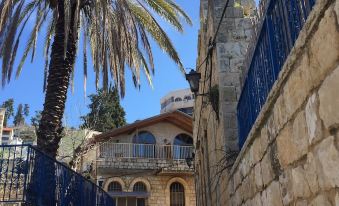 a stone building with a palm tree in front of it , and a street with a blue fence at Off The Square