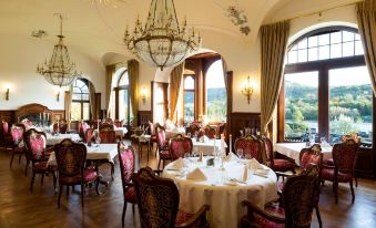 a large dining room with multiple tables and chairs , all set for a formal dinner at Schloss Lieser, Autograph Collection