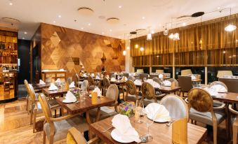 a restaurant with wooden tables and chairs , white plates , and gold accents is decorated in a modern style at Sofitel London Gatwick