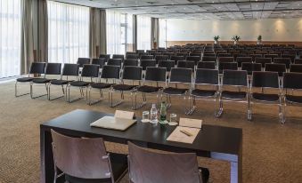 a large conference room with rows of chairs arranged in a semicircle , and a podium at the front of the room at Novotel Paris Nord Expo Aulnay
