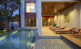 a modern house with a swimming pool in the backyard , surrounded by wooden decking and umbrellas at Mae Rim Grace