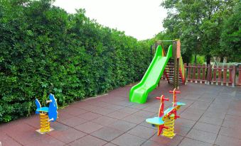 a colorful playground with a slide , swings , and other play equipment surrounded by green bushes at Nautilus
