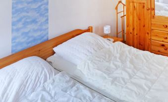 a bed with white sheets and a wooden headboard is in a room with blue clouds on the wall at Gila