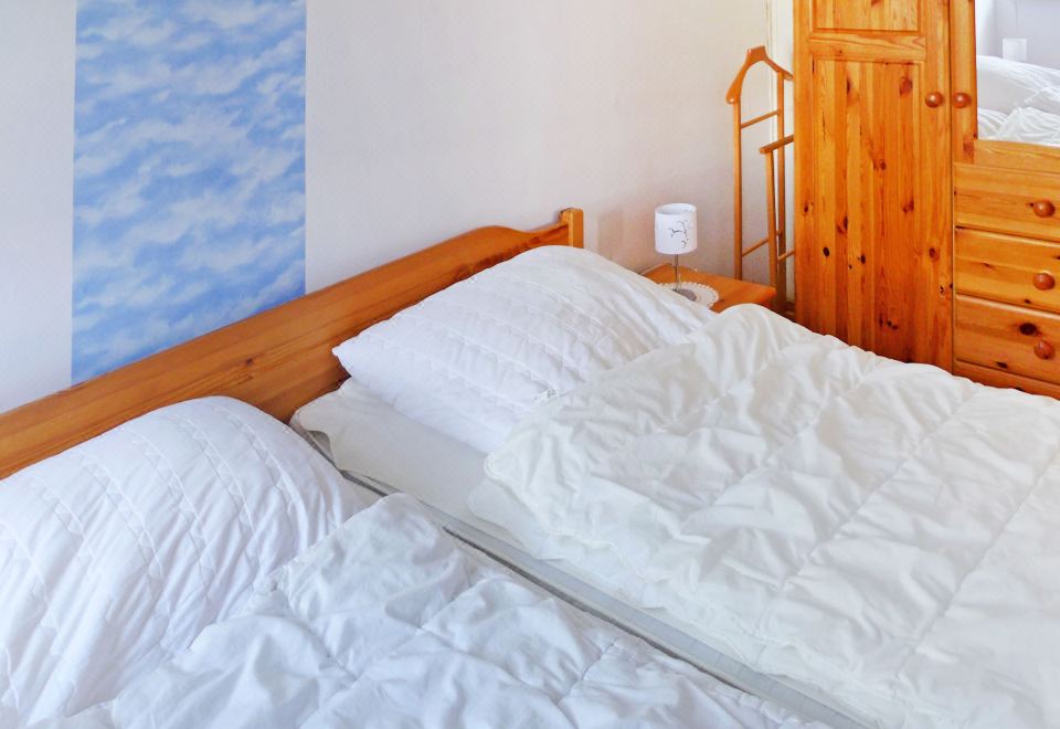 a bed with white sheets and a wooden headboard is in a room with blue clouds on the wall at Gila