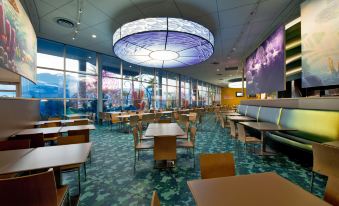 a large dining area with multiple tables and chairs , as well as a mural on the wall at Disney's Art of Animation Resort