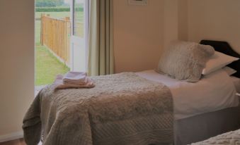 a room with two beds , one on the left and one on the right side of the room at Woodhouse Woodmancote