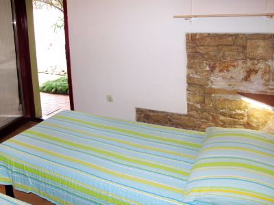 a bed with a blue and green striped comforter is in a room with a stone wall at Ingrid