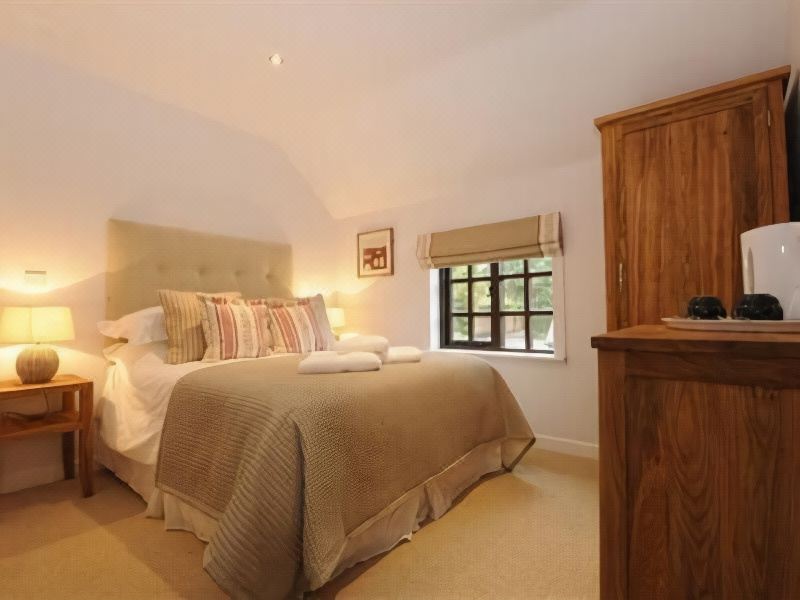 a spacious bedroom with a large bed , white walls , and a window with curtains , as well as a wooden desk in the corner at Barton B&B