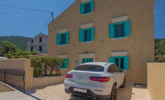 a white car parked in front of a beige house with blue shutters and a car parked nearby at Villa Mare